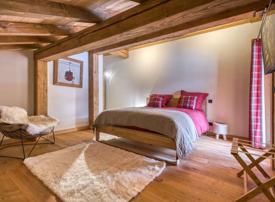 This cozy bedroom features a rustic design with exposed wooden beams and a warm, inviting atmosphere.