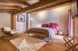 This cozy bedroom features a rustic design with exposed wooden beams and a warm, inviting atmosphere.