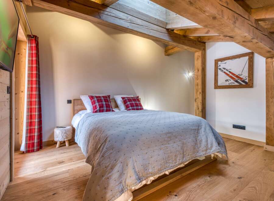 Experience rustic charm in this cozy bedroom featuring exposed wooden beams and a warm, inviting ambiance.