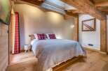 Experience rustic charm in this cozy bedroom featuring exposed wooden beams and a warm, inviting ambiance.