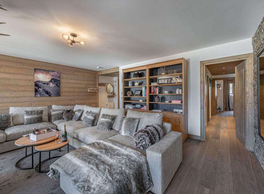 Experience luxury living in this stunning property, featuring a spacious living room with a cozy sectional sofa and a beautiful wooden wall.