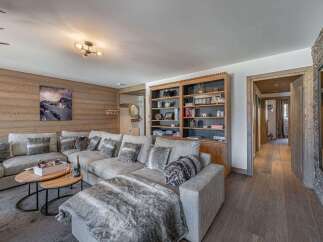 Experience luxury living in this stunning property, featuring a spacious living room with a cozy sectional sofa and a beautiful wooden wall.