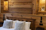 Experience rustic charm in this cozy bedroom featuring a stunning wooden headboard and paneling.