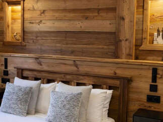 Experience rustic charm in this cozy bedroom featuring a stunning wooden headboard and paneling.