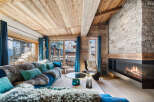 Experience luxury living in this stunning chalet, featuring a cozy living room with a fireplace and a plush sofa.