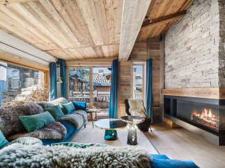 Experience luxury living in this stunning chalet, featuring a cozy living room with a fireplace and a plush sofa.