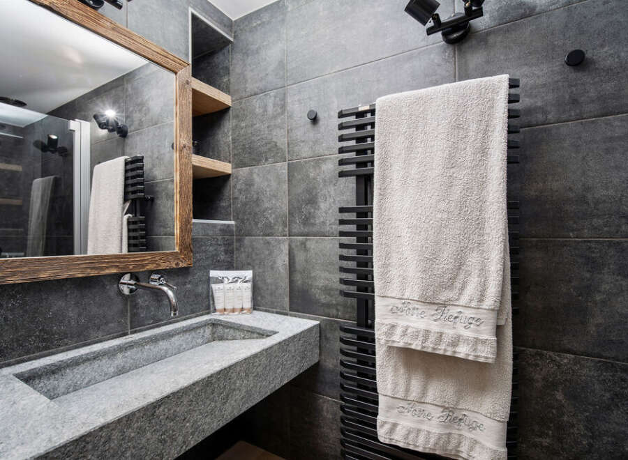 This modern bathroom features a sleek, gray stone sink and matching tiled walls, creating a sophisticated and minimalist aesthetic.
