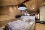 Experience luxury in this stunning bedroom featuring a unique moon-shaped pendant light and cozy bedding.