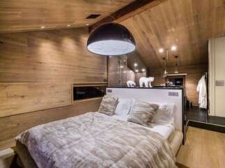 Experience luxury in this stunning bedroom featuring a unique moon-shaped pendant light and cozy bedding.