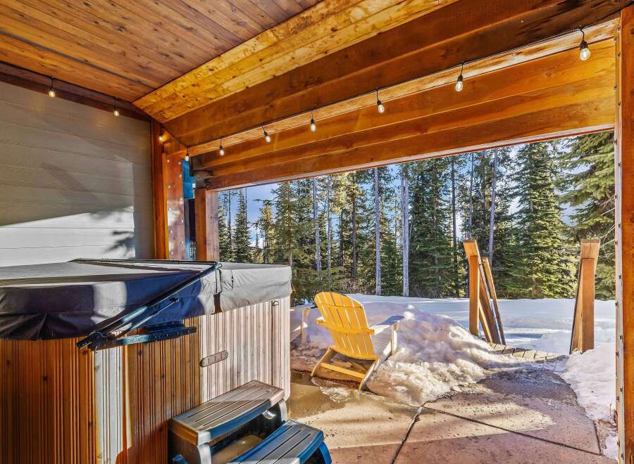 Enjoy the ultimate relaxation in this stunning outdoor space featuring a hot tub and a serene view of the surrounding forest.