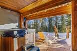 Enjoy the ultimate relaxation in this stunning outdoor space featuring a hot tub and a serene view of the surrounding forest.