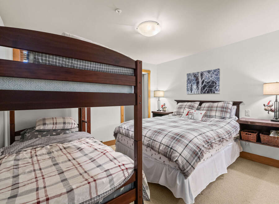 This cozy bedroom features a charming bunk bed and a comfortable queen-sized bed, perfect for accommodating guests or family.