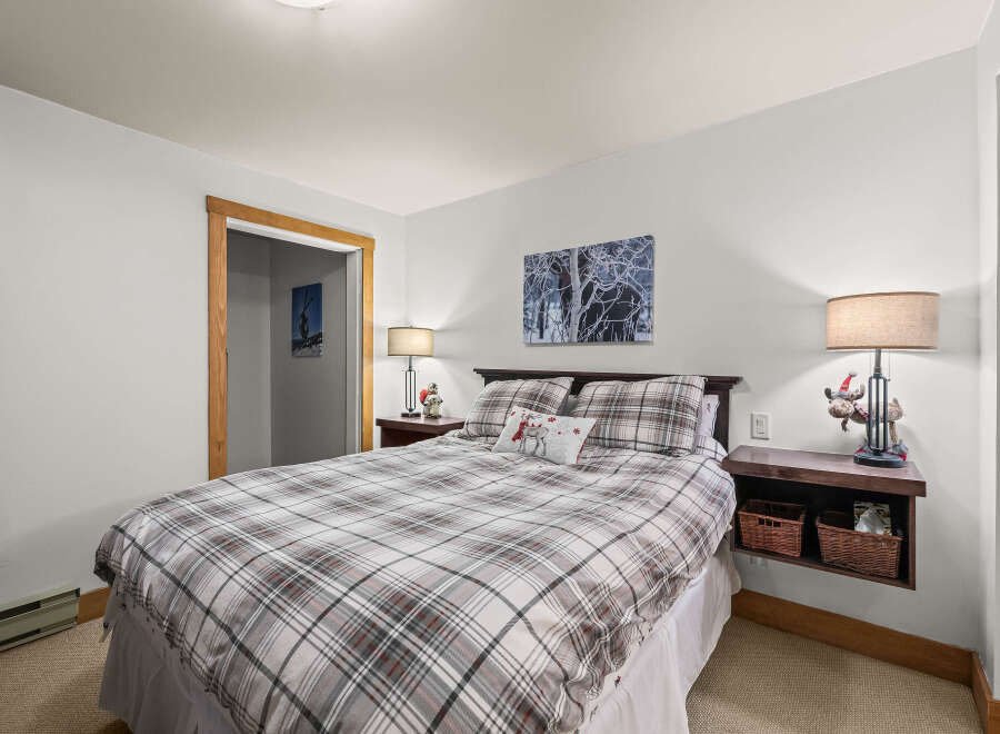 This cozy bedroom features a comfortable bed with a plaid comforter and decorative pillows, perfect for a relaxing retreat.