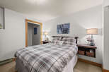 This cozy bedroom features a comfortable bed with a plaid comforter and decorative pillows, perfect for a relaxing retreat.