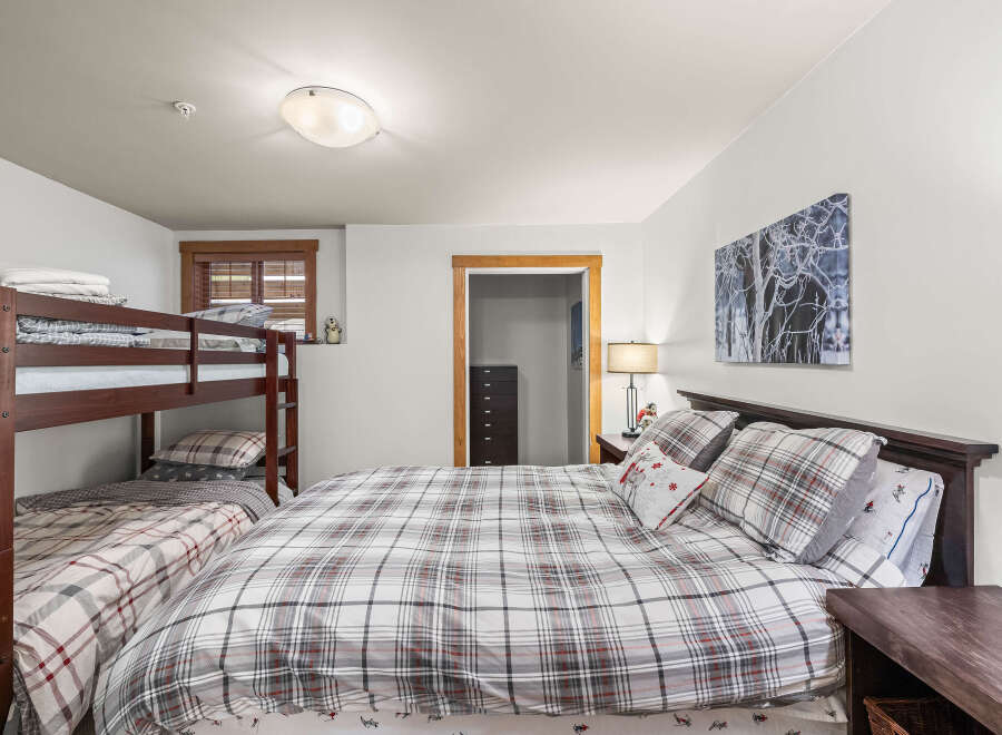 This cozy bedroom features a comfortable queen-sized bed with a plaid comforter, perfect for a relaxing night's sleep.