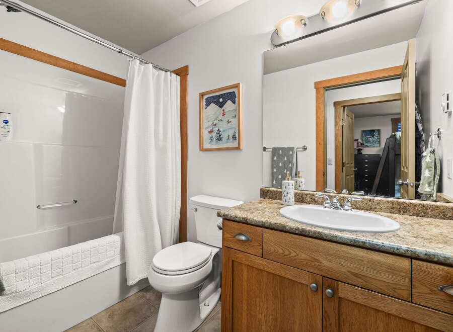 This charming bathroom features a cozy ambiance with its warm wooden cabinetry and a well-lit vanity area.
