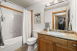 This charming bathroom features a cozy ambiance with its warm wooden cabinetry and a well-lit vanity area.