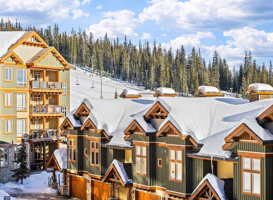Discover the charm of this stunning ski-in/ski-out property, featuring luxurious townhomes with snow-covered roofs and wooden accents.