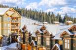 Discover the charm of this stunning ski-in/ski-out property, featuring luxurious townhomes with snow-covered roofs and wooden accents.