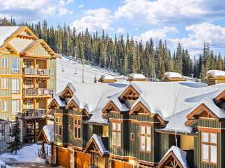 Discover the charm of this stunning ski-in/ski-out property, featuring luxurious townhomes with snow-covered roofs and wooden accents.