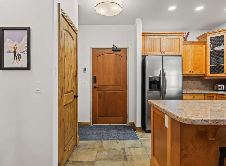 Step into this inviting entryway, featuring a beautiful wooden door and a stylish kitchen island.