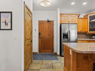 Step into this inviting entryway, featuring a beautiful wooden door and a stylish kitchen island.