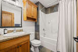 This stunning bathroom features a beautiful wooden vanity with a granite countertop, offering both style and functionality.