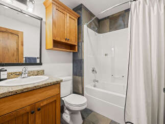 This stunning bathroom features a beautiful wooden vanity with a granite countertop, offering both style and functionality.