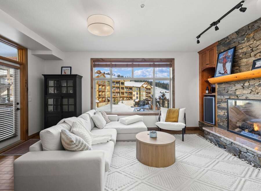 Experience luxury living in this stunning property, featuring a cozy living room with a fireplace and a large window offering breathtaking views.