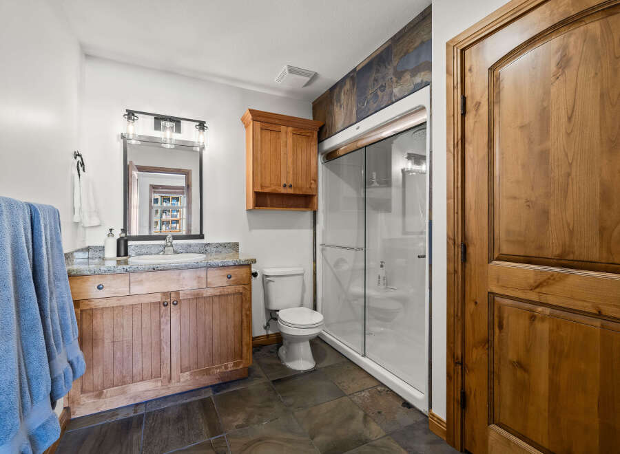 This stunning bathroom boasts a rustic charm with its wooden cabinetry and elegant stone flooring.