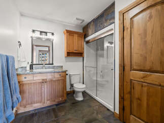 This stunning bathroom boasts a rustic charm with its wooden cabinetry and elegant stone flooring.
