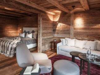 Experience rustic luxury in this stunning property, featuring a cozy bedroom with a plush bed and a separate living area.