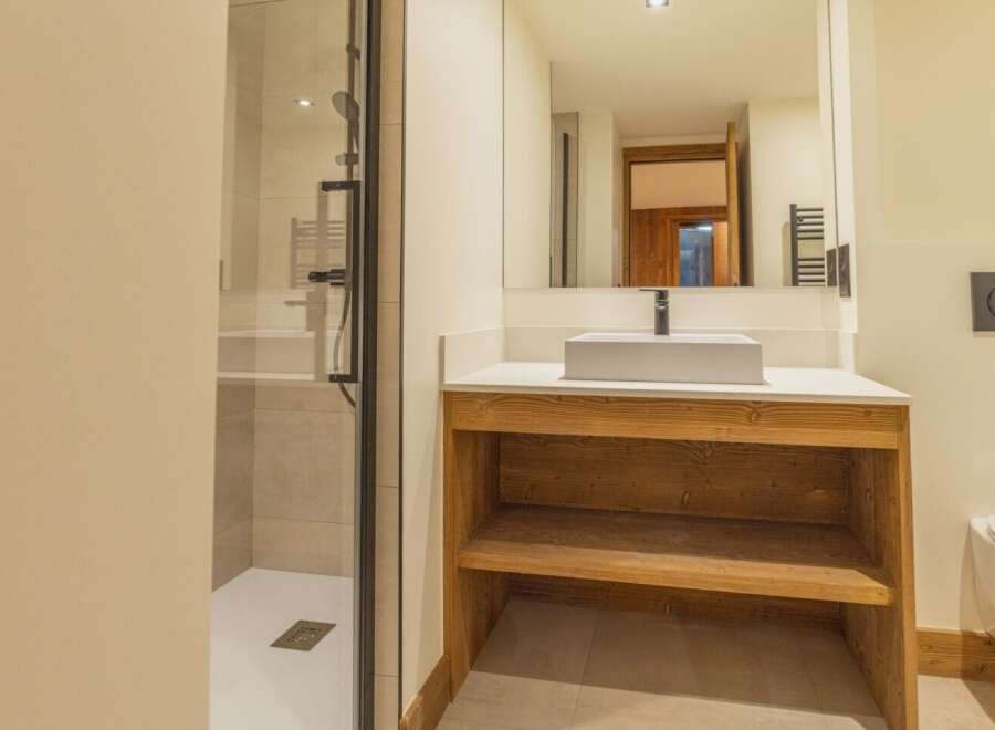 This modern bathroom features a sleek design with a spacious shower and a stylish wooden vanity.