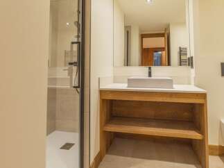 This modern bathroom features a sleek design with a spacious shower and a stylish wooden vanity.