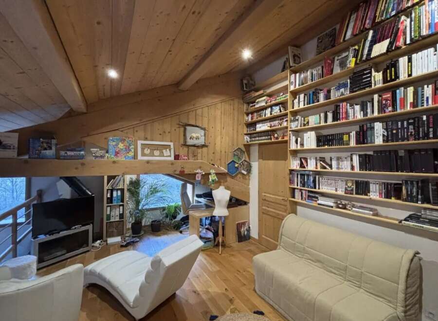 This charming property boasts a cozy living space with a unique architectural design, featuring exposed wooden beams and a loft-style layout.