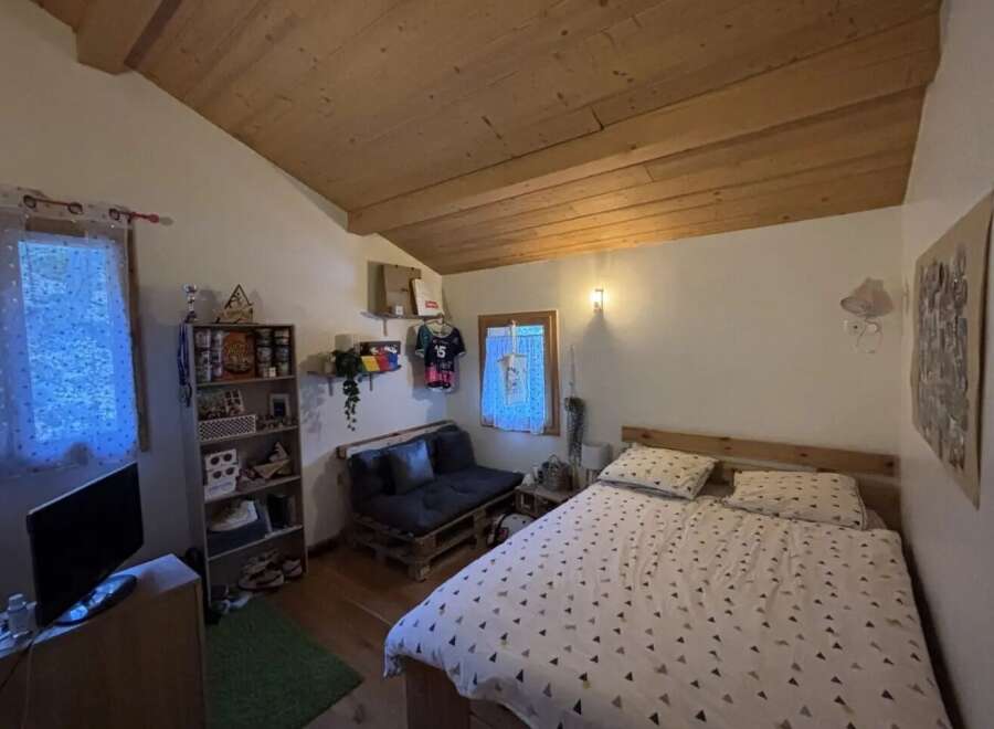 This cozy bedroom features a unique wooden ceiling and a comfortable bed, perfect for relaxation.