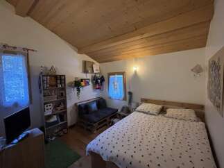 This cozy bedroom features a unique wooden ceiling and a comfortable bed, perfect for relaxation.