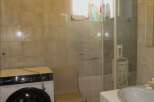 This bathroom features a practical layout with a washing machine and a shower.