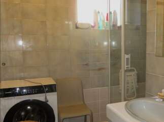 This bathroom features a practical layout with a washing machine and a shower.