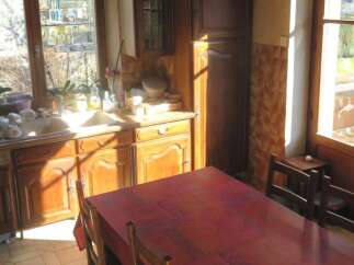 This charming kitchen features a warm, inviting atmosphere with its wooden cabinetry and a spacious dining table.