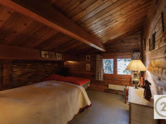 This cozy bedroom features a warm, inviting atmosphere with its wooden walls and ceiling.