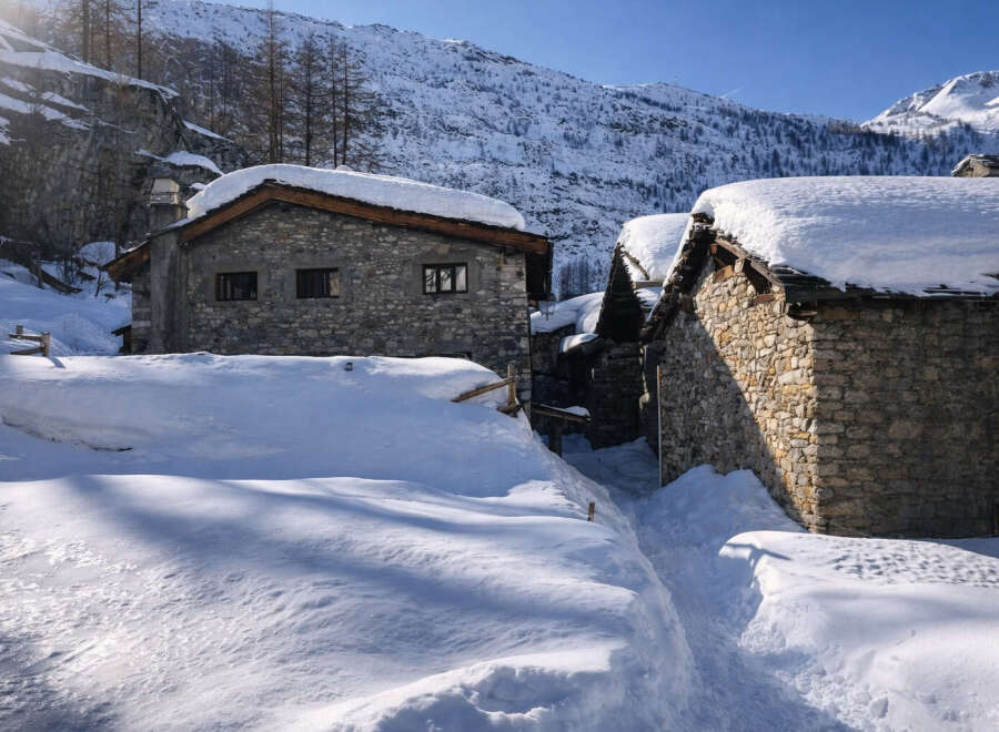 Discover this charming stone house nestled in a serene snowy mountain landscape.