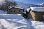Discover this charming stone house nestled in a serene snowy mountain landscape.