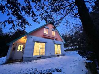 Nestled in a serene, snow-covered landscape, this charming house offers a cozy retreat.