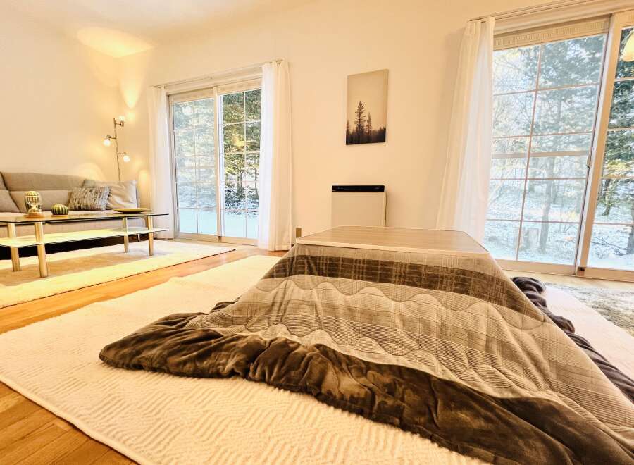 This cozy living space features a traditional kotatsu table, perfect for relaxing and enjoying the warmth.