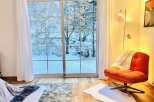 Enjoy the serene beauty of this cozy living space, featuring a stunning view of a snow-covered landscape through large sliding glass doors.