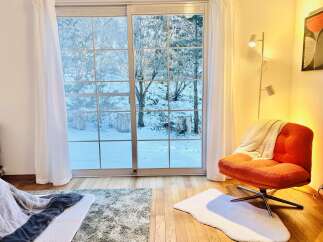 Enjoy the serene beauty of this cozy living space, featuring a stunning view of a snow-covered landscape through large sliding glass doors.