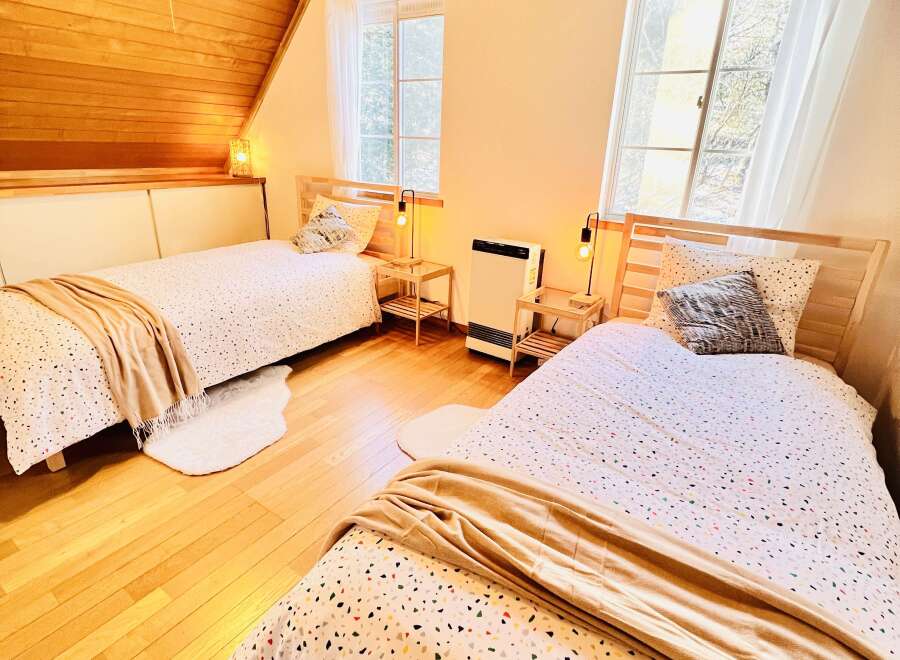 This cozy bedroom features two twin beds with stylish bedding and soft throws, perfect for a comfortable stay.