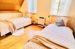 This cozy bedroom features two twin beds with stylish bedding and soft throws, perfect for a comfortable stay.