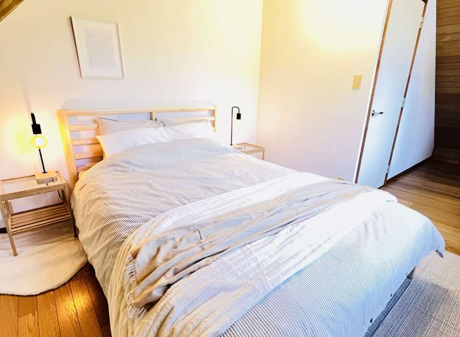 This cozy bedroom features a comfortable bed with a striped comforter and a soft blanket, perfect for a relaxing retreat.